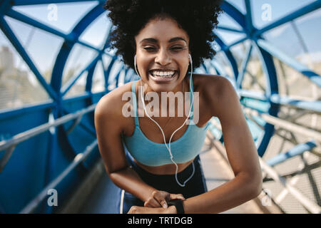 Junge fitness Frau mit smart Watch suchen bei Kamera und lächelnd. Sportlerin einrichten Ihr smart Watch vor einem Lauf. Stockfoto