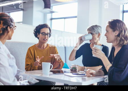 Gruppe von vier Frauen, die eine Diskussion im Büro. Weibliche Fachleute sitzen um einen Tisch und Brainstorming über neue Business Plan. Stockfoto