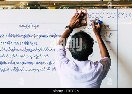 Yangon, Myanmar - März 2019: burmesische Mann schreiben Tempel Zeremonie Zeitplan auf der Tafel in der shwedagon Stupa Stockfoto