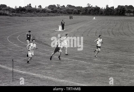 1950, historische, jungen männlichen Athleten in einem Wettlauf außerhalb konkurrierenden auf einer Grasbahn in einem großen Feld, England, UK. Stockfoto