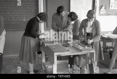 1950, historische, Schülerinnen eine holzarbeit Klasse, mit Planern auf eine Werkbank, mit einem männlichen Lehrer helfen einem Schüler, England, Großbritannien Stockfoto