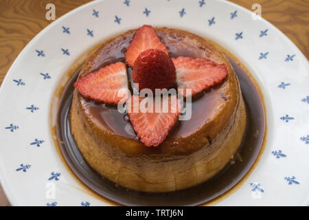 Nahaufnahme einer Flan mit Erdbeeren und Karamell auf einer Platte Stockfoto