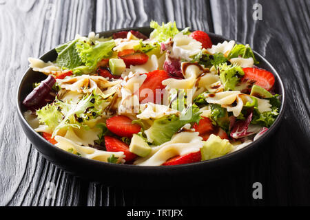 Gesunde Salate von farfalle Nudeln mit Avocado, Erdbeeren, frischem Salat und Balsamico sauce Close-up auf einem Teller auf den Tisch. Horizontale Stockfoto