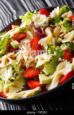 Sommer Pasta Salat mit Avocado, Erdbeeren, Salat, mit Balsamico Sauce schließen gekleidet - bis auf einen Teller auf dem Tisch. Vertikale Stockfoto