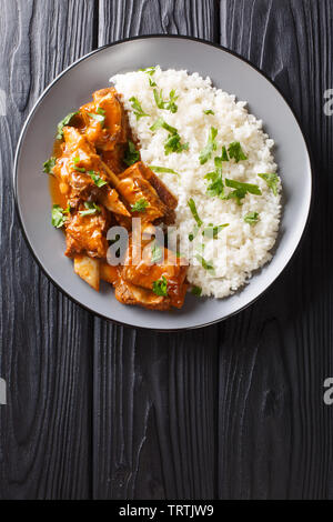 Geschmorte Rippchen in pikanter Soße mit Reis in der Nähe serviert auf einem Teller. Vertikal oben Ansicht von oben Stockfoto