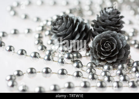 In der Nähe von drei silberne Kegel und Perlen Kette auf weißem Hintergrund Stockfoto