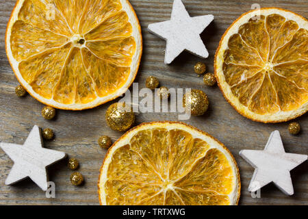 Weihnachten Komposition mit drei getrockneten Orangen, drei weiße Sterne und golden glitter Kugeln auf Holz- Hintergrund - close-up Stockfoto