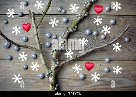 Weihnachtsbaum Konzept mit blattlosen Zweige, Schneeflocken, rote Herzen, Silber glitter Kügelchen und Silber Perlen Kette auf Holz- Hintergrund Stockfoto