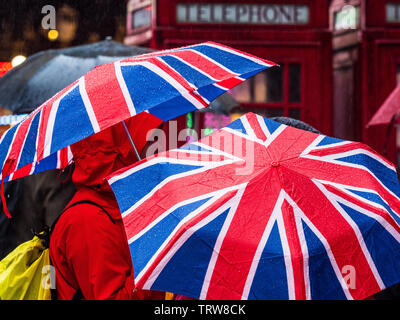 Union Jack schirms im Regen in London. Touristen tragen in Central London Flaggenschirme von Union Jack. Stockfoto