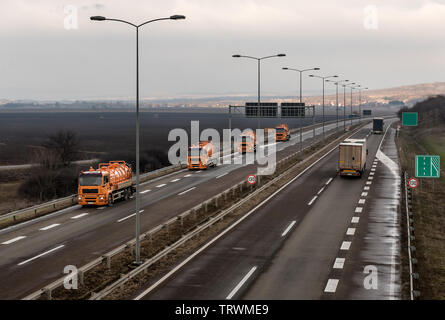 Konvoi oder Wohnwagen von Tankwagen auf einer kurvigen Landstraße durch die ländliche Landschaft Stockfoto