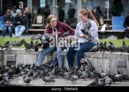 Zwei Mädchen füttern Tauben in Piccadilly, Manchester, UK Stockfoto