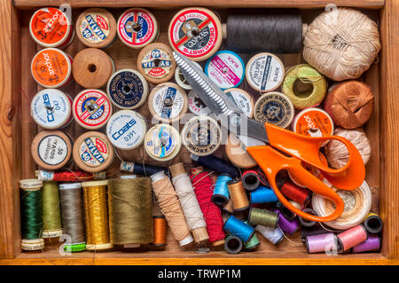 Kurzwaren oder nähen Elemente in einer Schublade abgelegt - Walzen aus Baumwolle und Gewinde mit einer Schere. Stockfoto