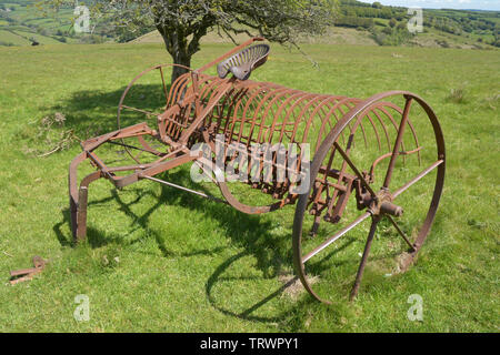 Heu rechen auf ein Feld in Exmoor zurückgezogen, umgerechnet von Pferden gezogenen am Traktor angetrieben. Exford, Somerset UK Stockfoto