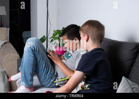 Boys Spiele spielen auf ihre Handys zu Hause Stockfoto