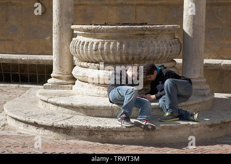 Zwei Kinder Hängen am Fuße der Brunnen, Piazza Pio II, Pienza, Toskana, Italien Stockfoto