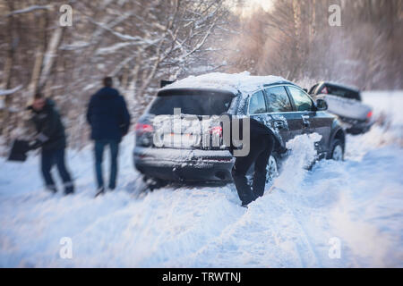 Vorher suv-Auto im Schnee stecken, Männer graben und den Wagen aus Schnee, Konzept der Winter Probleme mit dem Auto Stockfoto