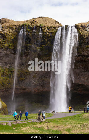 SELJALANDSFOSS, ISLAND - Touristen am Wasserfall auf der südlichen Küste, auf Seljalands River. Stockfoto