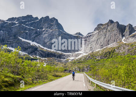 Weibliche Radfahrer auf der Straße nach Nusfjord, Lofoten, Norwegen. Stockfoto