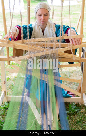 Moskau, Russland, 12. Juni 2019. Mädchen weaver. Blau und grün Threads in einem alten Holz- Maschine. Stockfoto