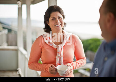 Lächelnde Frau mittleren Alters mit einem Freund auf einer Veranda. Stockfoto