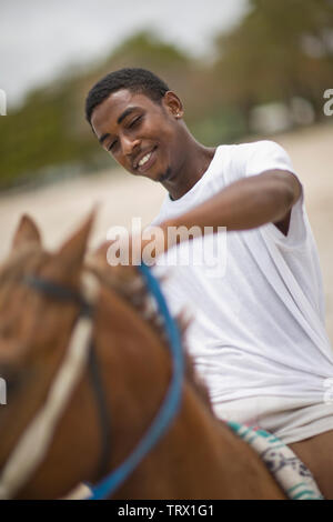Lächelnd Teenager halten die Zügel beim Reiten ein braunes Pferd. Stockfoto