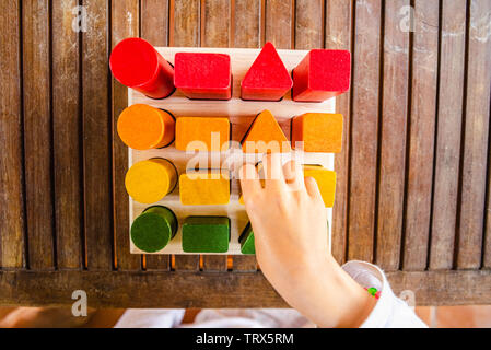 Satz von Bausteinen aus Holz von Sequenzen von geometrischen Formen mit Naturfarben bemalt, von oben gesehen, die motorische Entwicklung der Kinder zu helfen. Stockfoto