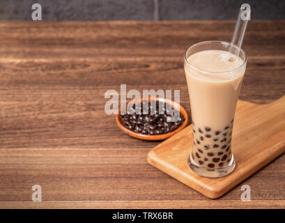 Beliebte Taiwan Getränk - Bubble Milch Tee mit Tapioka Perlen Kugel in Glas und Stroh, Holz- Tabelle grau Ziegelstein Hintergrund, Nahaufnahme, kopieren Raum Stockfoto
