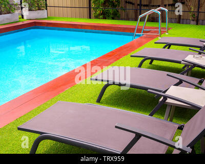 Sonnenliegen auf grünem Gras und bars Leiter schnappen Sie sich am Außenpool. Stockfoto