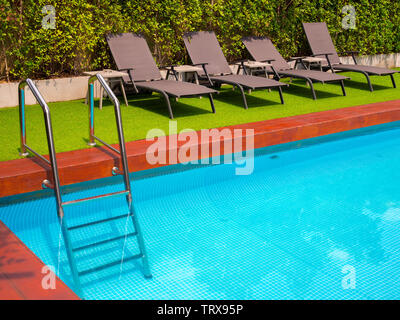 Sonnenliegen auf grünem Gras und bars Leiter schnappen Sie sich am Außenpool im Garten mit kopieren. Stockfoto