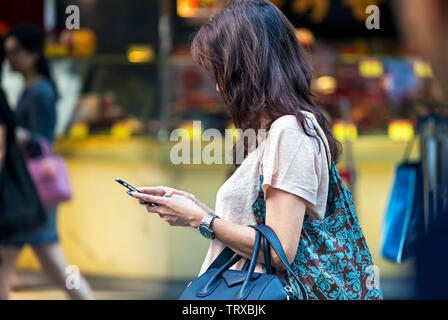 Frau Konzentration auf Handy in der Straße, Hong Kong, SAR, China Stockfoto