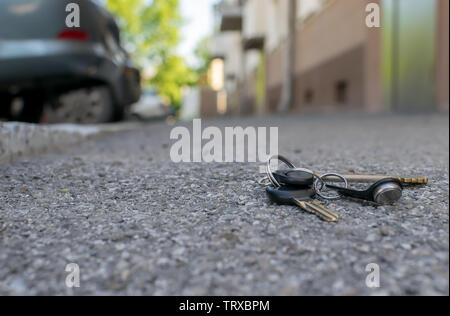 Die verlorenen Schlüsselbund liegt auf der asphaltierten Gehweg der Straße, in der Nähe der Eingang eines Hauses, die mit dem geparkten Autos Stockfoto