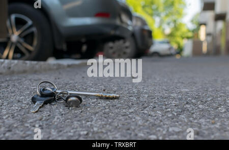 Die verlorenen Schlüsselbund liegt auf der asphaltierten Gehweg der Straße, in der Nähe der Eingang eines Hauses, die mit dem geparkten Autos Stockfoto