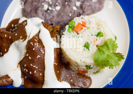 Mexicanischen Mole Sauce mit Huhn, Reis und schwarze refried Beans. Traditionelle Speisen aus Oaxaca und anderen südlichen Staaten auf Mexiko, nahe mit Kopie sp Stockfoto