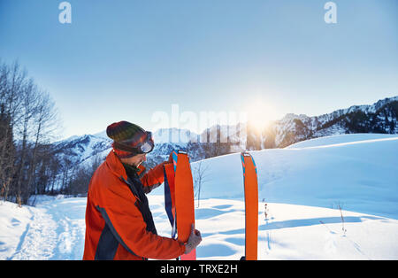 Mann Camus auf seine orange Skier für Skitouren in den Bergen bei Sonnenaufgang Stockfoto