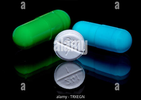 Makro Bild eines grünen Pille, blaue Pille und einem weißen Pille auf eine reflektierende Oberfläche. Arzneimittel auf dem Display. Stockfoto