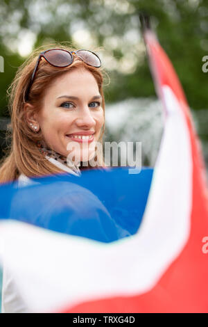 Glückliche junge natürliche Frau mit Smile holding Flagge der Niederlande im Park, Schärfentiefe Stockfoto