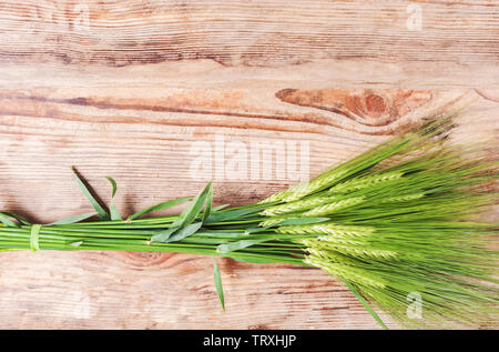 Kreative Gestaltung der grünen Ohren von Roggen über Holz- Hintergrund. Getreideernte auf dem Tisch. Flach, Konzept Bild für verschiedene Zwecke. Stockfoto