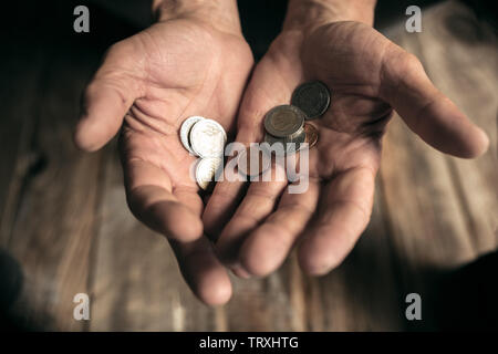 Männliche Bettler Händen Geld, Münzen aus menschlichen Freundlichkeit auf dem Holzboden an öffentlichen Weg oder die Straße Gehweg. Obdachlosen Armen in der Stadt. Probleme mit Finanzen, Wohnort. Stockfoto