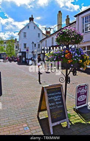 Hübsche Blumen/Blumenschmuck. Anchor Inn im Hintergrund. Menschen zu Fuß die Straße runter im Sonnenschein ein Sommertag. Stockfoto