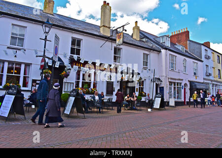 Personen, die sich ausserhalb der Anchor Inn, einem traditionellen Public House in alten Fore Street, Sidmouth. Andere wandern durch die Geschäfte zu erkunden. Stockfoto