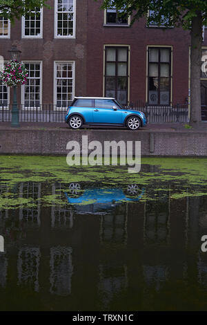 Blau Mini Cooper Auto an einem Kanal im Zentrum der Stadt im Wasser widerspiegelt geparkt Stockfoto