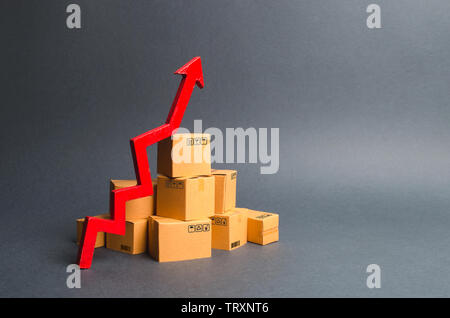 Ein Stapel von Kartons und einem grünen Pfeil nach oben. Das Wachstum der Produktion von Waren und Produkten, die zunehmende wirtschaftliche Indikatoren. Steigender Konsum Stockfoto