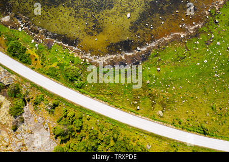 Von oben nach unten Luftbild der Insel gras Shoreline mit Felsbrocken übersät. Eine Landstraße Schnitte durch die Landschaft. Lage Blekinge in Schweden. Stockfoto