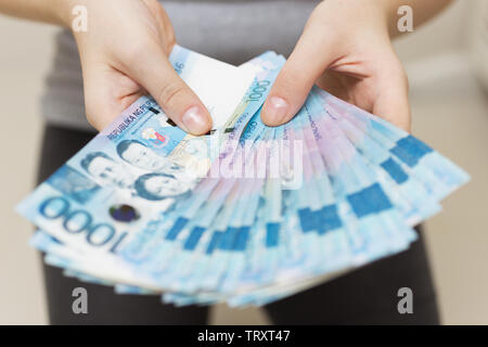 Hände halten Gehalt oder Payment Bundle von Bargeld von tausend philippinischen Peso, als wenn sein Reich. Zeigen Sie, Rechnungen bezahlen oder Bestechung geben. Stockfoto