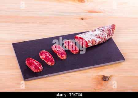 Spanisch fuet, eine trockene Wurst typische in Katalonien Region, in Scheiben geschnitten auf einer hölzernen Küchentisch Stockfoto