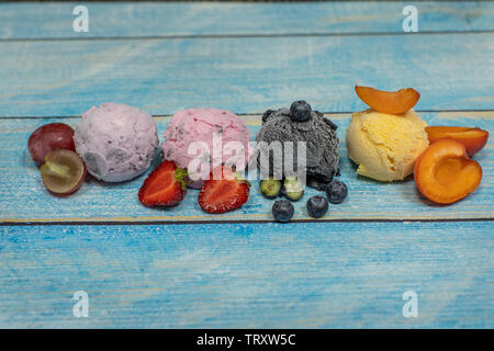 Süßes Eis in Kugeln auf einem Holz- Hintergrund. Verschiedene Aromen Beeren und Früchten. Platz kopieren Stockfoto