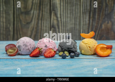 Süßes Eis in Kugeln auf einem Holz- Hintergrund. Verschiedene Aromen Beeren und Früchten. Platz kopieren Stockfoto