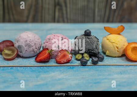 Süßes Eis in Kugeln auf einem Holz- Hintergrund. Verschiedene Aromen Beeren und Früchten. Platz kopieren Stockfoto