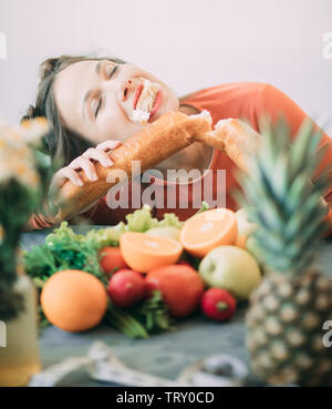 Junge Frau auf einer Diät erlag der Versuchung und leidenschaftlich beißt eine lange weiße knusprige Brot. Das Konzept der Diät, gesunde Ernährung und die Ablehnung von Ba Stockfoto