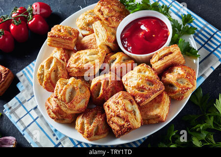 Blätterteig Brötchen mit gehacktem Hühnerfleisch und Pilze mit Ketchup und Petersilie auf einem weißen Teller auf einen konkreten Tisch serviert, Ansicht von oben Stockfoto